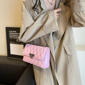 Elegante borsa a tracolla rosa trapuntata con catena e fibbia su un trench coat beige
