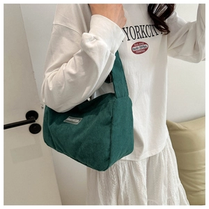 Dettaglio di una borsa a tracolla in velluto a coste verde scuro con etichetta