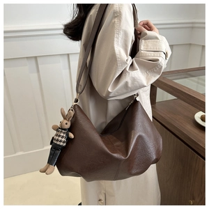 Detail einer dunkelbraunen Hobo-Tasche aus Kunstleder mit süßem Hasen-Anhänger für Damen
