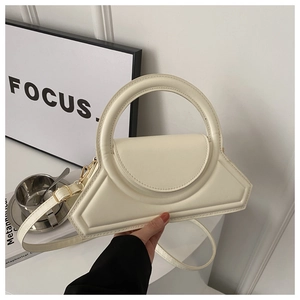 Detail of minimalist beige geometric handbag with round top handle and crossbody strap