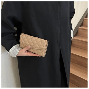 Close-up of beige quilted leather long wallet with diamond stitching and metal zipper detail