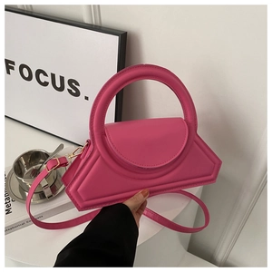 Detail of rose pink PU leather handbag with gold hardware and circular top handle