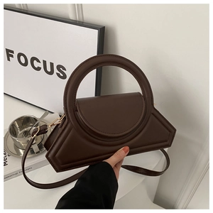 Detail of dark brown geometric handbag with oversized round handle and smooth leather