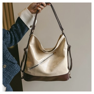 Détail du sac hobo en cuir beige avec finitions marron et fermeture éclair diagonale
