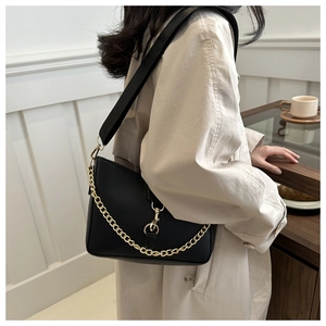 Gros plan d'un sac à bandoulière en cuir noir mat avec chaîne dorée et sangle nylon