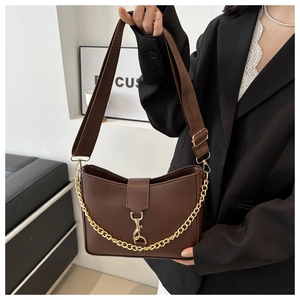 Detail of dark brown bucket bag featuring a decorative gold chain and wide nylon strap