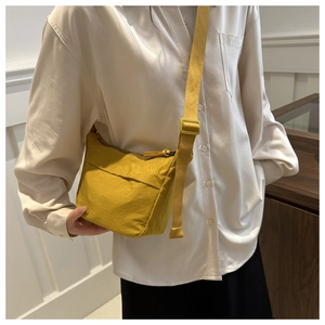 Close-up of a yellow nylon crossbody bag with adjustable strap worn by a female model