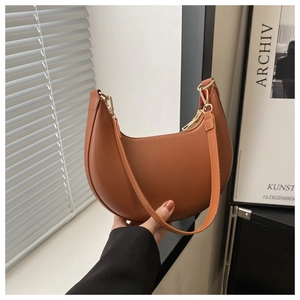 Détail du sac demi-lune marron avec texture en cuir lisse et fermeture éclair dorée élégante