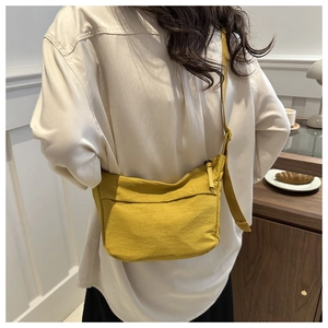 Close-up of ginger yellow nylon crossbody bag on a model with minimalist lifestyle decor