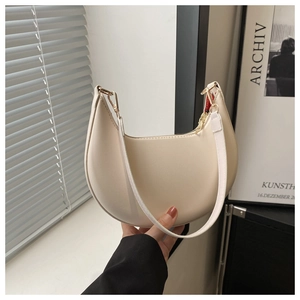 Détail d'un sac sous le bras demi-lune beige crème en cuir lisse et boucles dorées