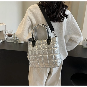Detailed view of silver quilted tote bag on model showing size and modern fashion style