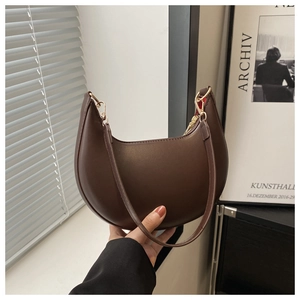Détail du sac demi-lune marron foncé avec fermeture éclair dorée et doublure rouge vif