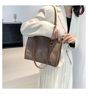 Detail view of large dark brown tote bag with marble texture and metal rivet accents