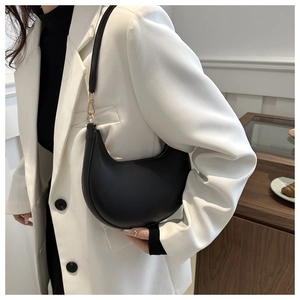 Détail d'un sac sous le bras en forme de croissant noir mat avec des boucles dorées