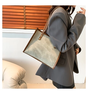 Detail of vintage tote bag with leather trim and metal rivets on model's shoulder