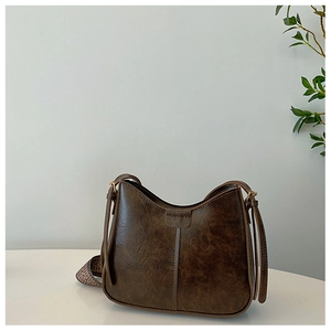 Détail du sac seau marron vintage avec texture similicuir et bandoulière tissée à motifs