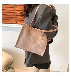 Detail of beige suede tote bag with pink trim and gold rivet hardware on shoulder strap