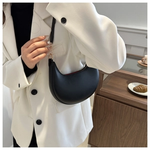 Détail du sac croissant en cuir noir montrant la doublure intérieure rouge vif