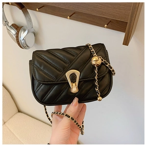 Detalle del bolso bandolera acolchado negro con cierre de escudo dorado y correa de cadena