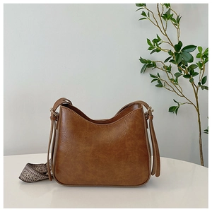 Gros plan sur le cuir marron et la bandoulière géométrique du sac seau tendance