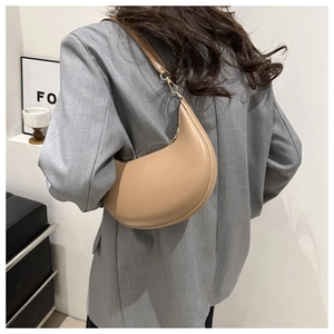 Sac hobo beige en forme de croissant porté sur un mannequin avec un costume gris