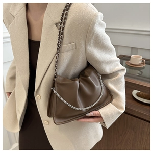 Detail of dark brown leather shoulder bag featuring silver chain and woven strap