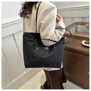 Detail of a large black nylon tote bag with Fashion & Bags leather patch and long handles