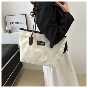 Detail of white nylon tote bag with brown leather trim and Fashion & Bags embossed tag