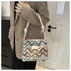 Detailed view of knitted bucket bag with colorful wavy patterns and white leather logo