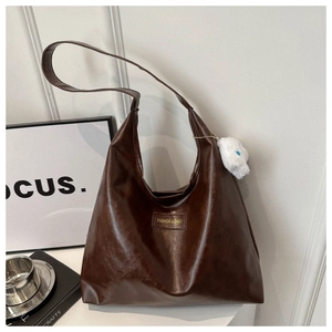 Detalle de bolso tote de cuero PU marrón con etiqueta de moda y llavero de conejo
