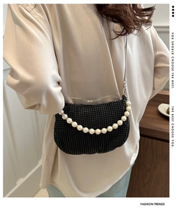 Detail of black sequined crossbody bag with pearl chain and shimmering crystal surface