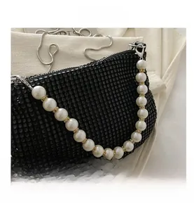 Detail of black rhinestone handbag featuring pearl top handle and silver snake chain