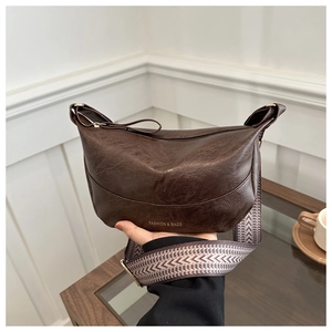 Dettaglio borsa a mezzaluna marrone scuro con tracolla jacquard e scritte dorate fini