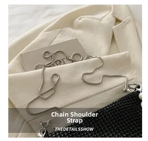 Detail of silver chain strap on black beaded fashion bag with elegant pearl accents