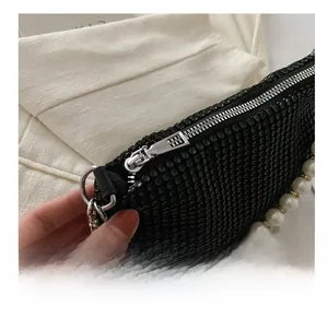 Detail of smooth silver zipper and large pearl chain on black rhinestone handbag