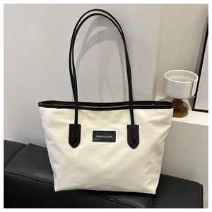 Close-up of contrast leather straps and fashion label on white oxford tote bag
