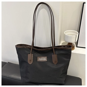 Detail of high-density black nylon tote with contrast brown leather logo and handles