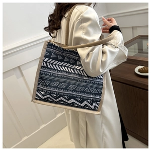 Close-up of geometric pattern tote bag with brown straps shown on shoulder