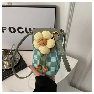 Détail du sac de téléphone à carreaux vert menthe avec fleur jaune et pompons