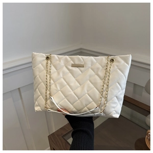 Detail einer weißen gesteppten Shopper-Tasche mit goldener Kette und Metallakzent