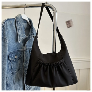 Détail d'un sac cabas noir en nylon avec poche plissée élastique et large bandoulière
