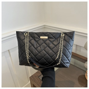 Detail der schwarzen Stepptasche mit goldener Kette und strukturierter Lederoptik