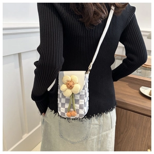 Détail d'un sac de téléphone à damier avec fleur jaune porté par le mannequin