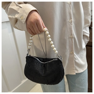 Detail of black rhinestone handbag with pearl handle and silver chain on model