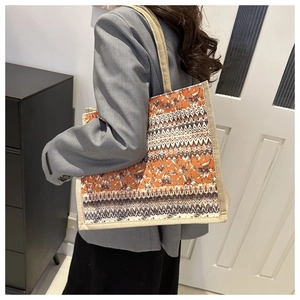 Detail shot of linen tote bag featuring orange ethnic patterns and woven shoulder straps