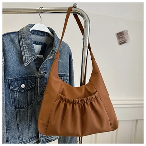 Détail d'un grand sac fourre-tout marron caramel avec poche avant à plis élastiques
