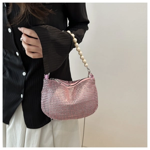 Close-up of pink rhinestone handbag with pearl handle and metal chain detail