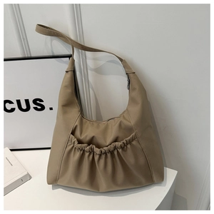 Détail du sac cabas en nylon kaki montrant la poche avant plissée et la texture imperméable