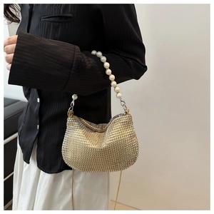Close-up of golden rhinestone evening bag with elegant pearl handle and metal chain