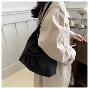 Détail du grand sac cabas noir avec poches latérales à cordon et texture en nylon soyeux